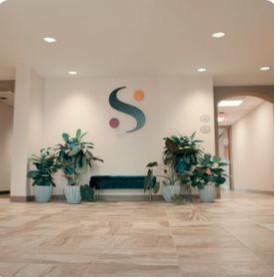 Synergy Center for Wellbeing lobby — warm, plant-filled waiting area